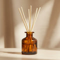 Brown glass diffuser bottle with wooden sticks on a dark gray background
