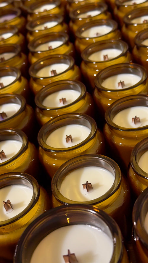 Multiple candles in glass jars arranged in rows.