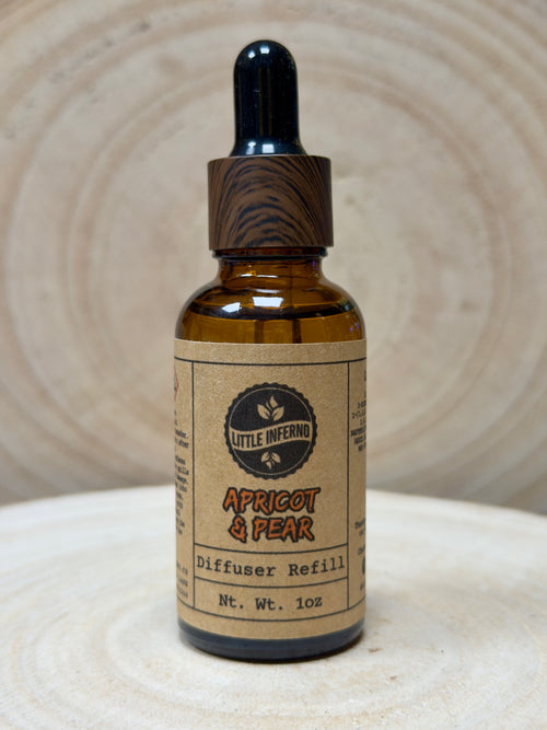 Brown glass bottle with dropper labeled 'Apricot & Pear' diffuser refill on a textured surface.