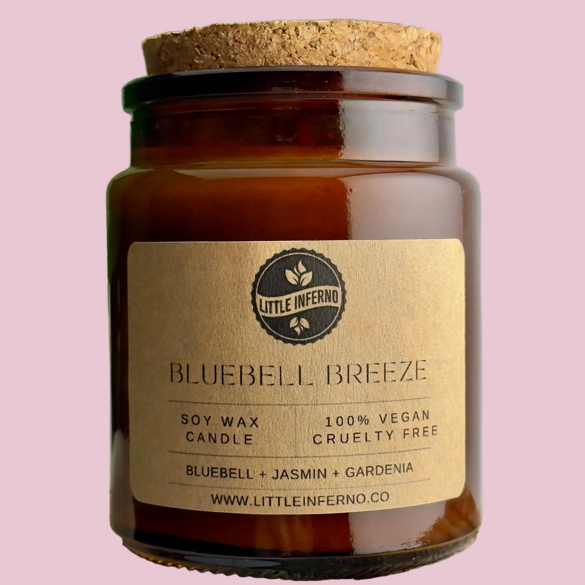 Candle jar labeled 'Bluebell Breeze' with a cork lid on a pink background