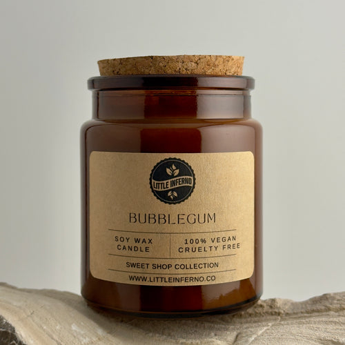 Brown candle jar with cork lid and 'Little Inferno' label on a neutral background