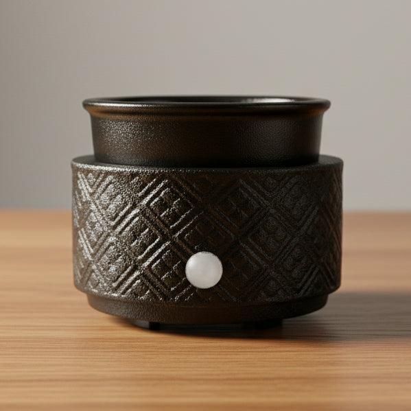 Black textured ceramic warmer on a wooden surface with a neutral background