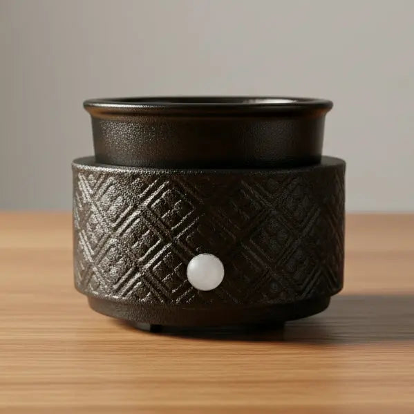 Black textured ceramic warmer on a wooden surface with a neutral background