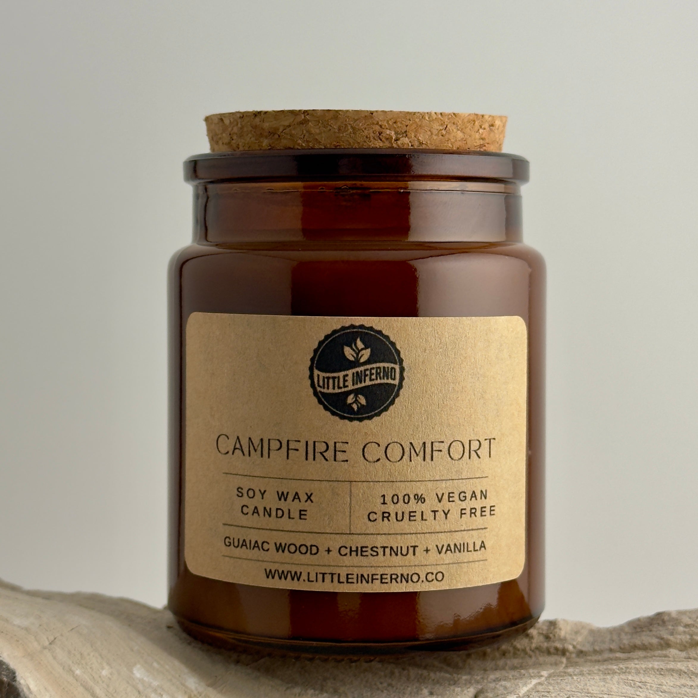Brown candle jar with cork lid and 'Little Inferno' label on a light background