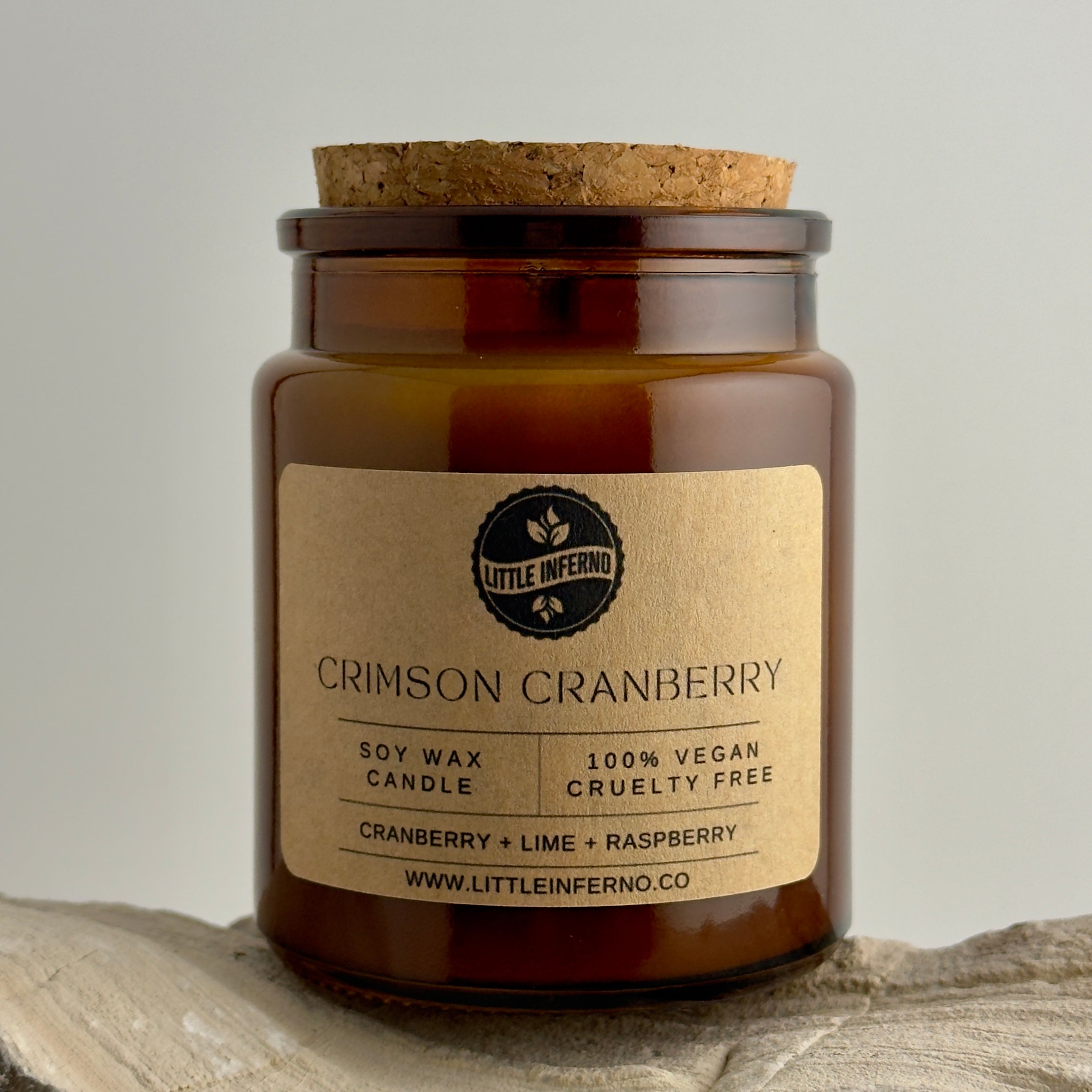 Candle jar with a cork lid and 'Little Inferno' label on a neutral background