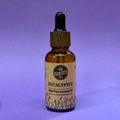Bottle of Eucalyptus essential oil with a dropper on a purple background
