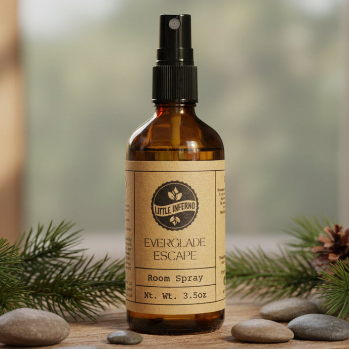 Brown spray bottle labeled 'Everglade Escape' on a wooden surface with greenery and stones.