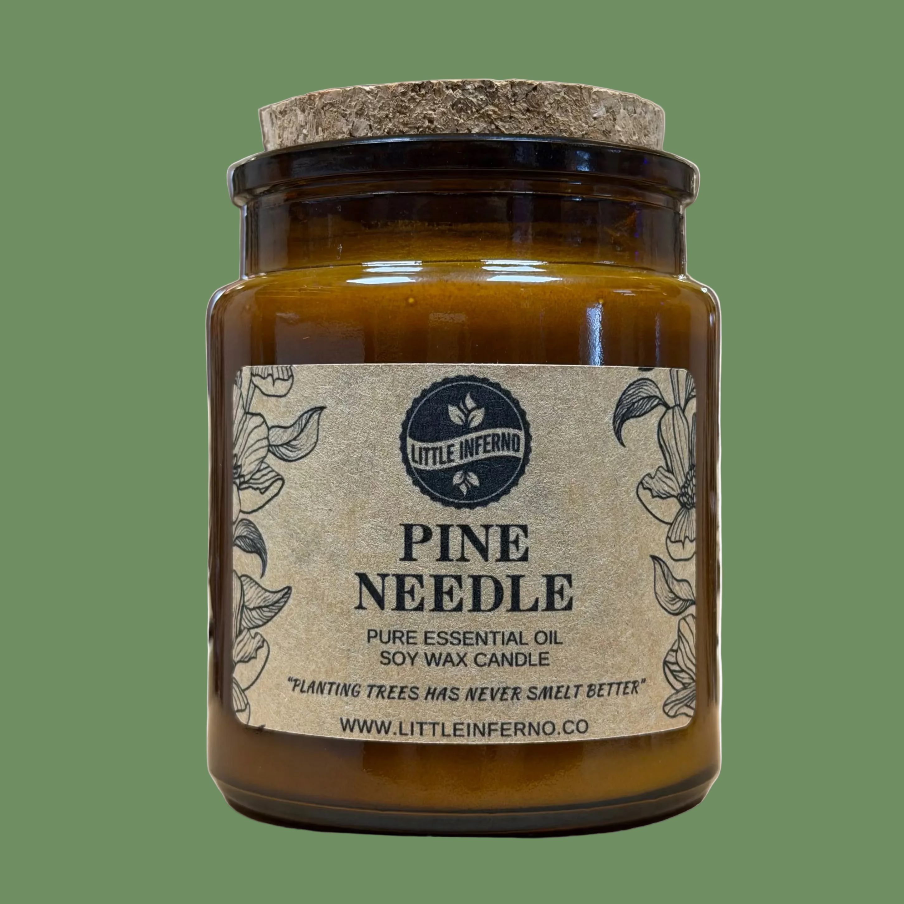 A jar candle labeled 'PINE NEEDLE' by Little Inferno, made from pure essential oil soy wax, in an amber glass jar with a cork lid, set against a softly blurred background.