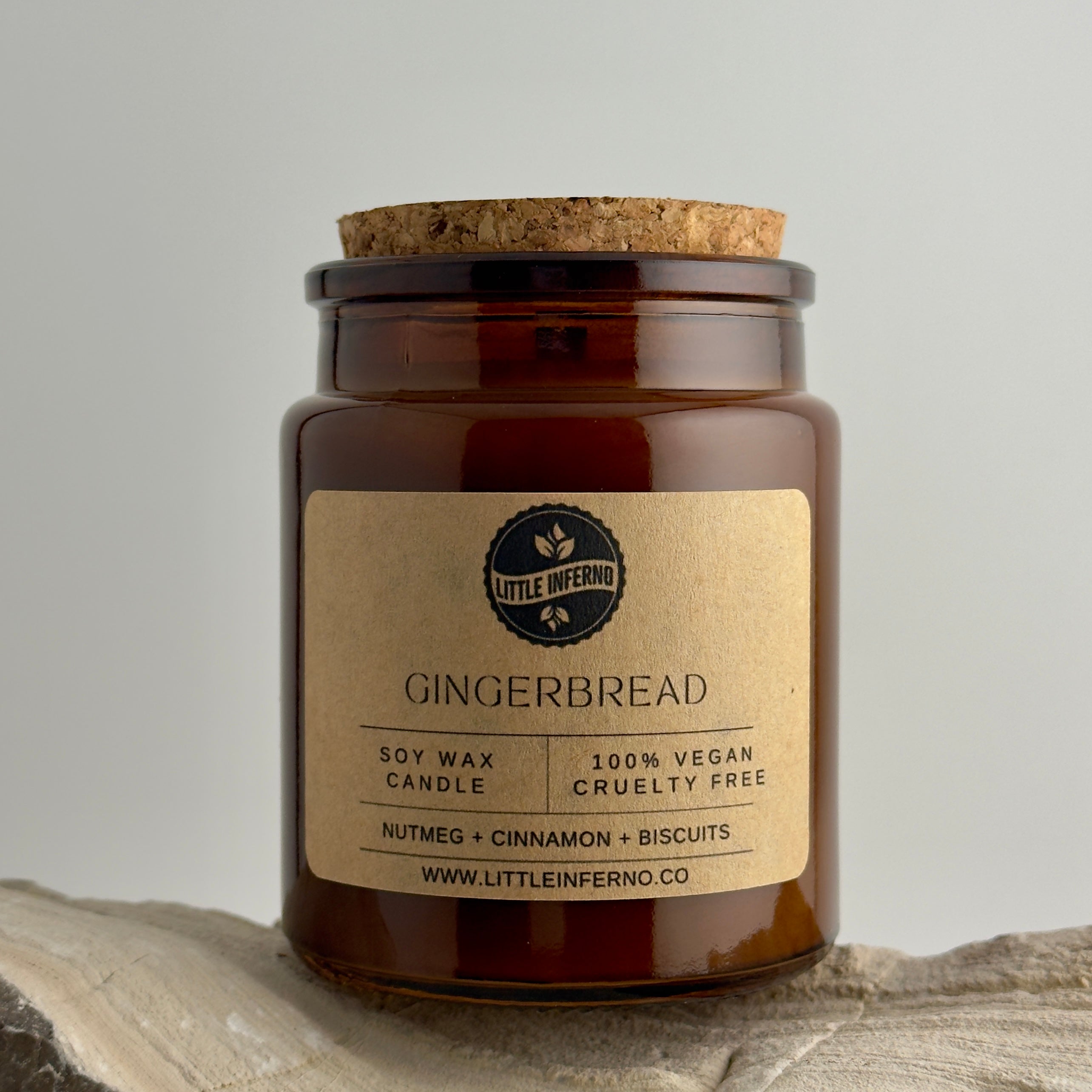 Gingerbread candle in a brown jar with a cork lid on a stone surface.