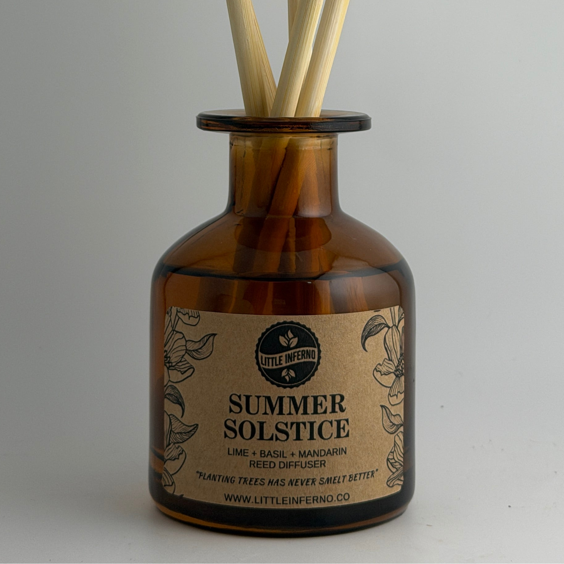 Amber glass reed diffuser bottle with natural wood reeds, featuring a vintage-style label that reads 'SUMMER SOLSTICE'.