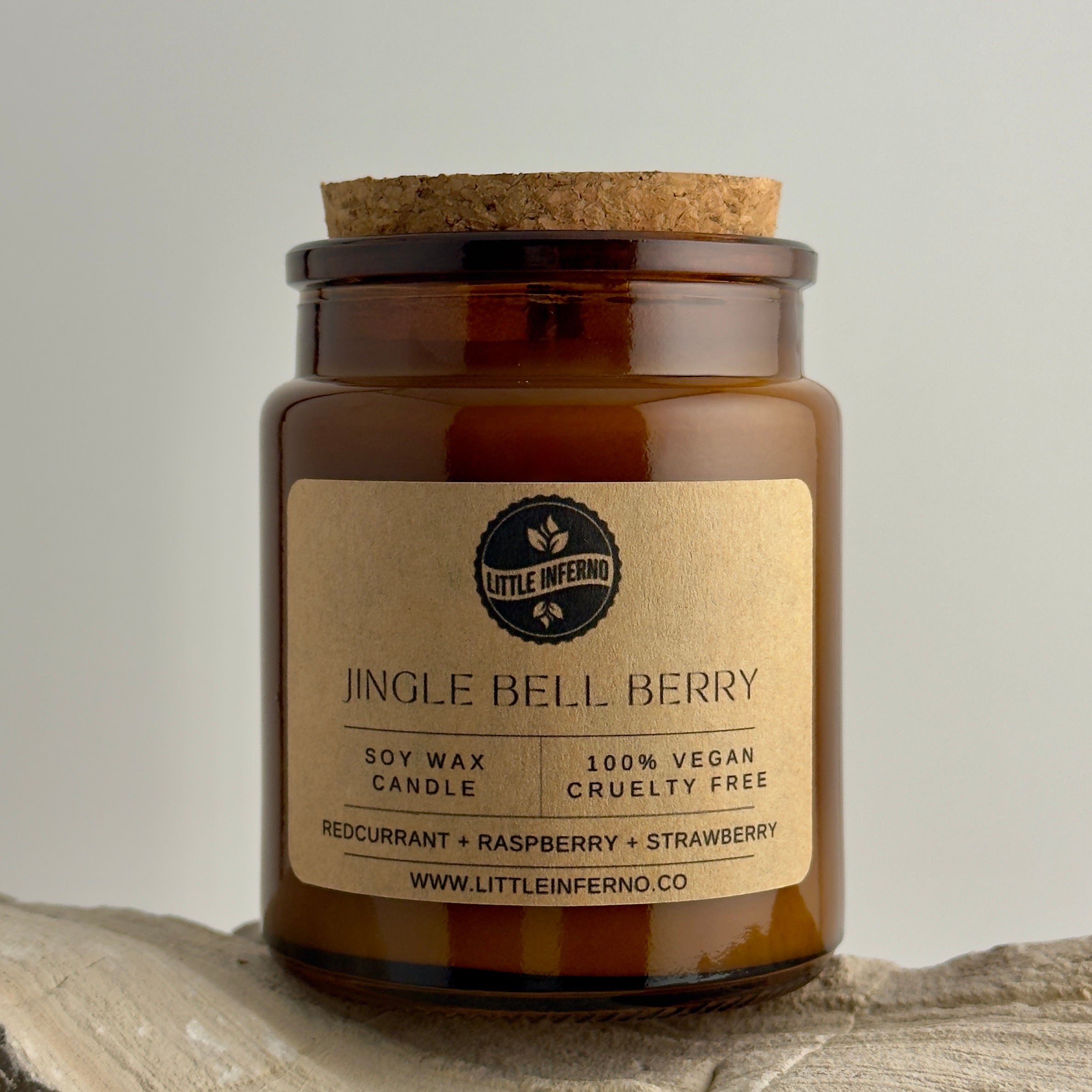 Scented candle jar labeled 'Jingle Bell Berry' by Little Inferno on a neutral background