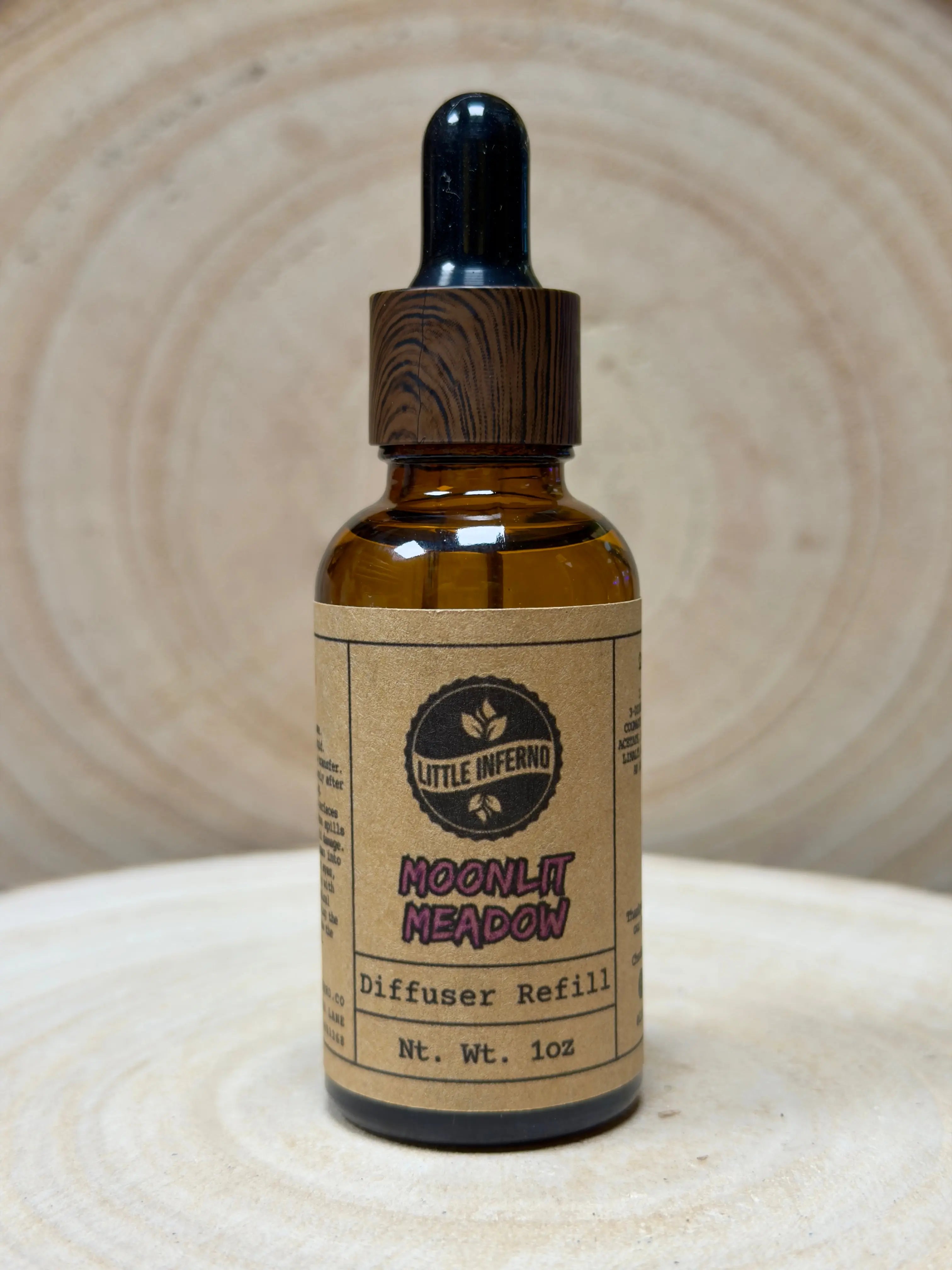 Bottle of 'Little Inferno Moonlit Meadow' diffuser refill on a textured surface