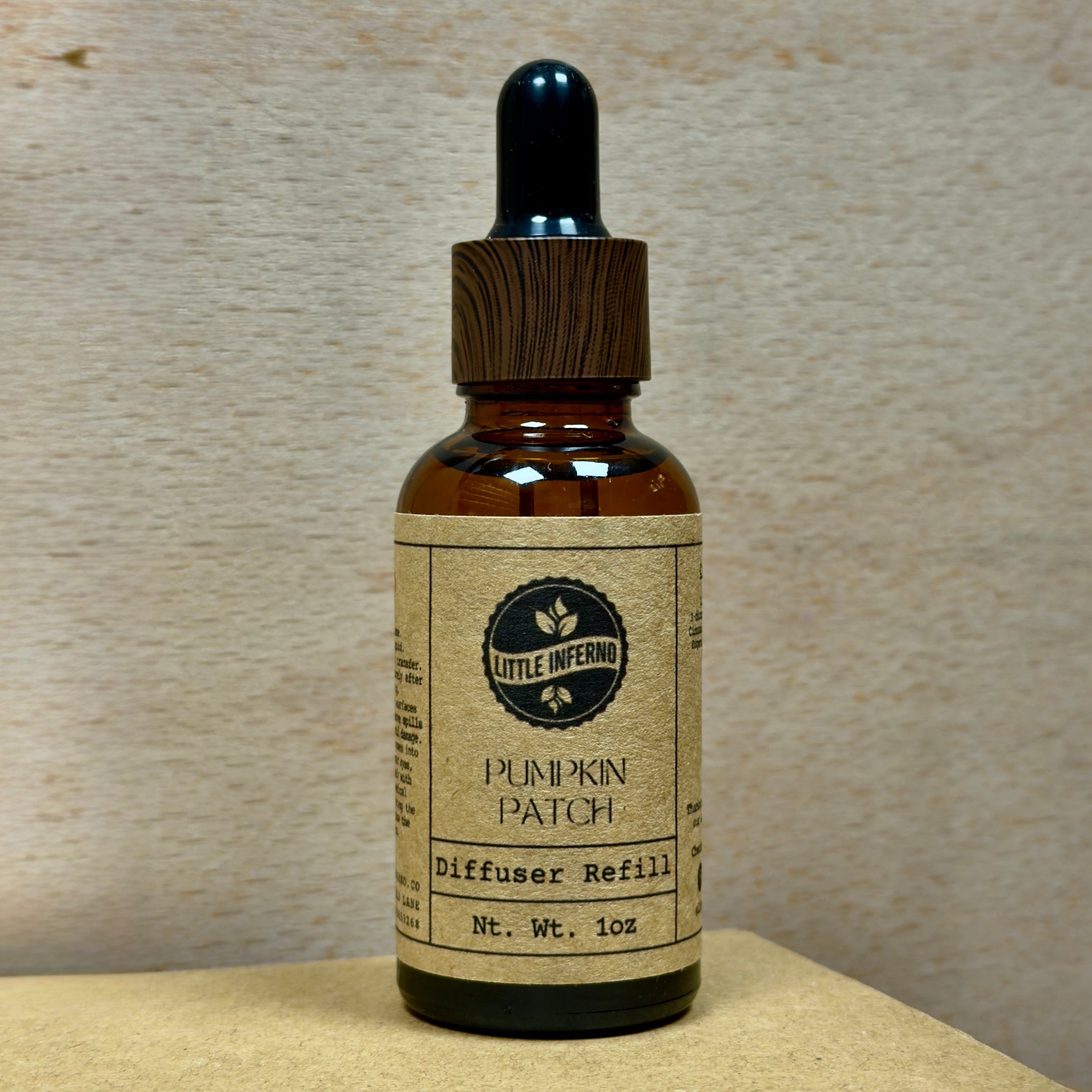Bottle of 'Pumpkin Patch' diffuser refill with a wooden dropper on a neutral background