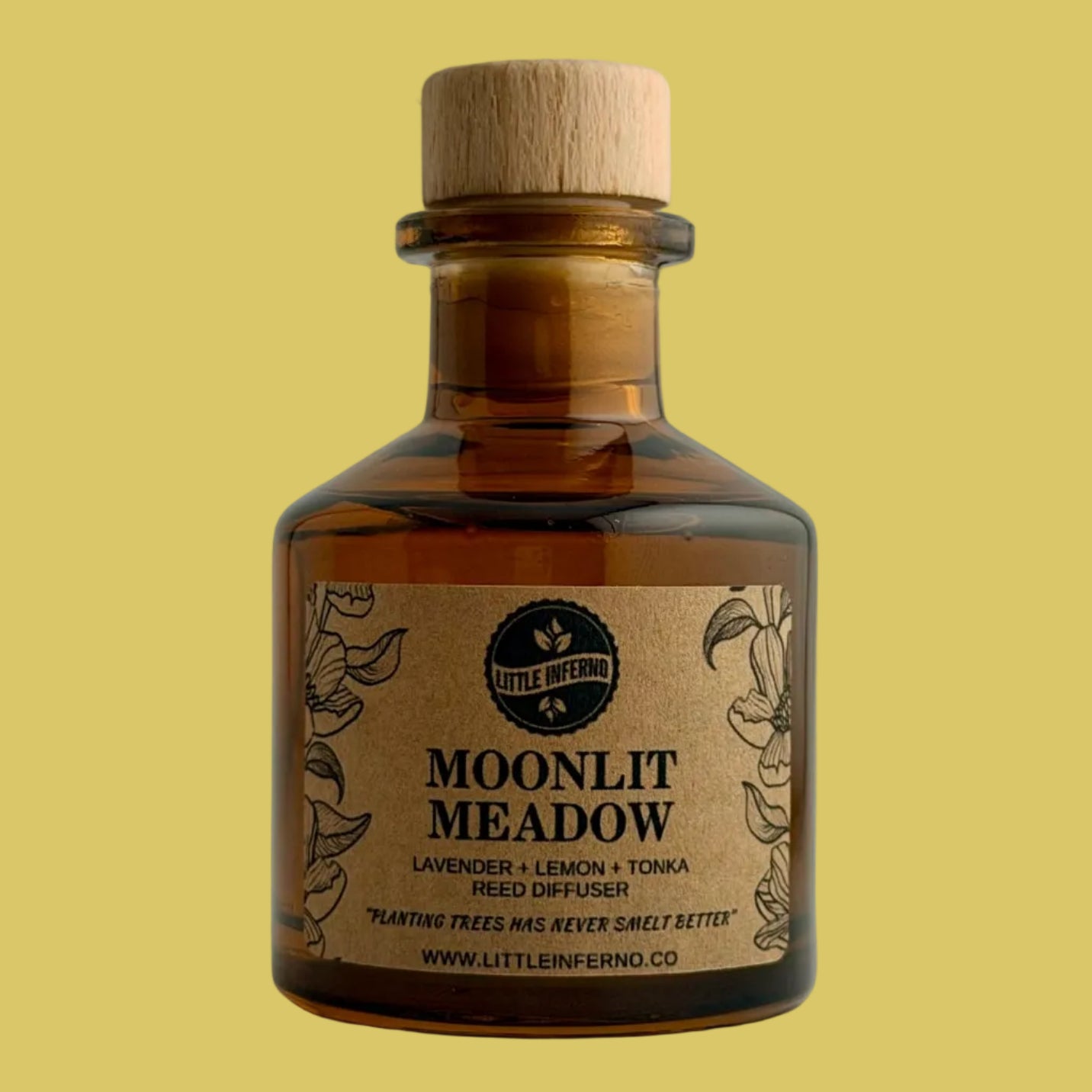 A small amber glass bottle with a light wood cork stopper and a kraft paper label reading 'MOONLIT MEADOW' by Little Emperor, photographed against a plain light gray background.
