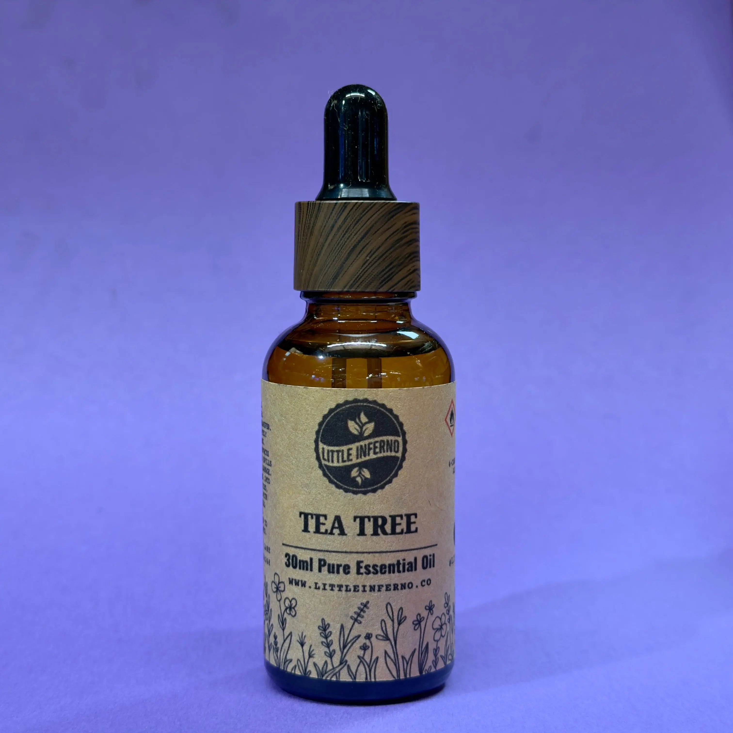 Tea tree essential oil bottle with dropper on a purple background