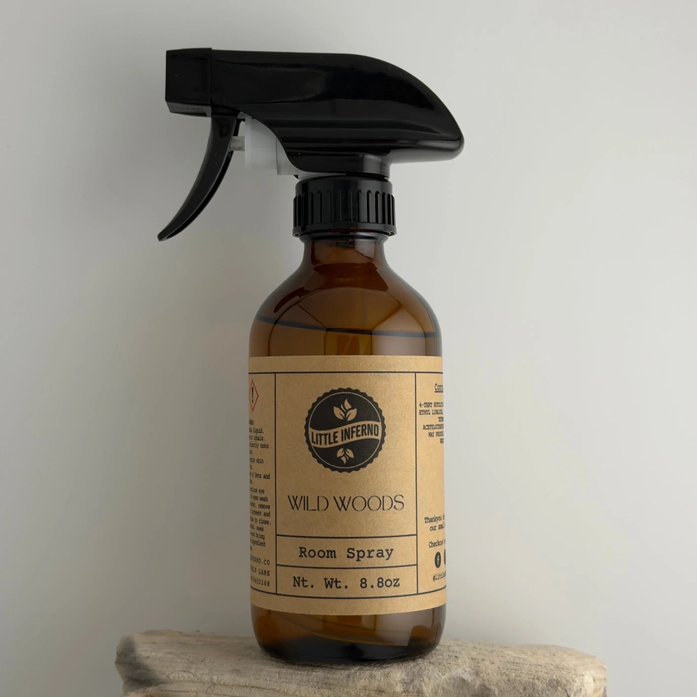 Brown spray bottle with black nozzle labeled 'Wild Woods' on a neutral background