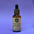 Bottle of Ylang Ylang essential oil with a label on a purple background