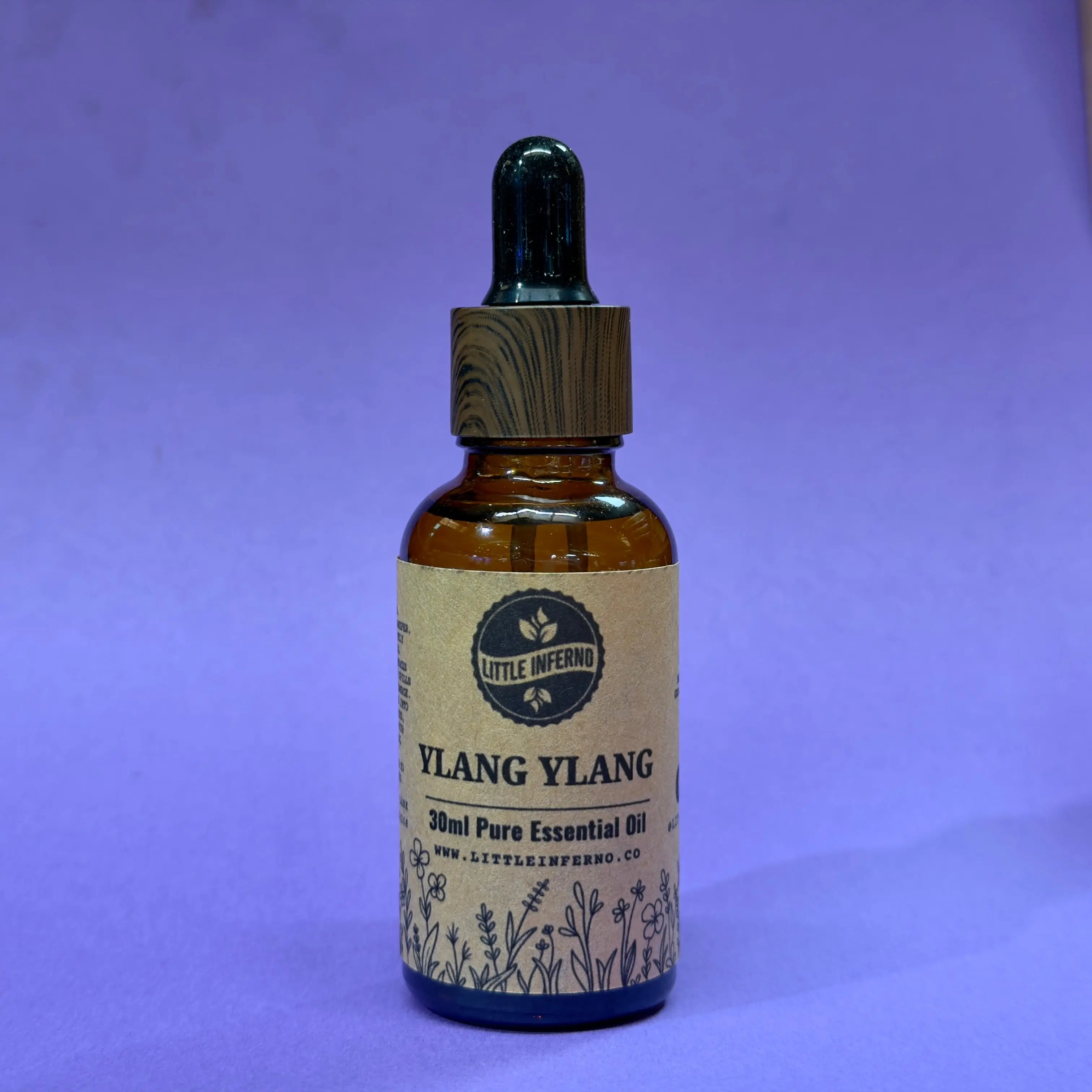 Bottle of Ylang Ylang essential oil with a label on a purple background