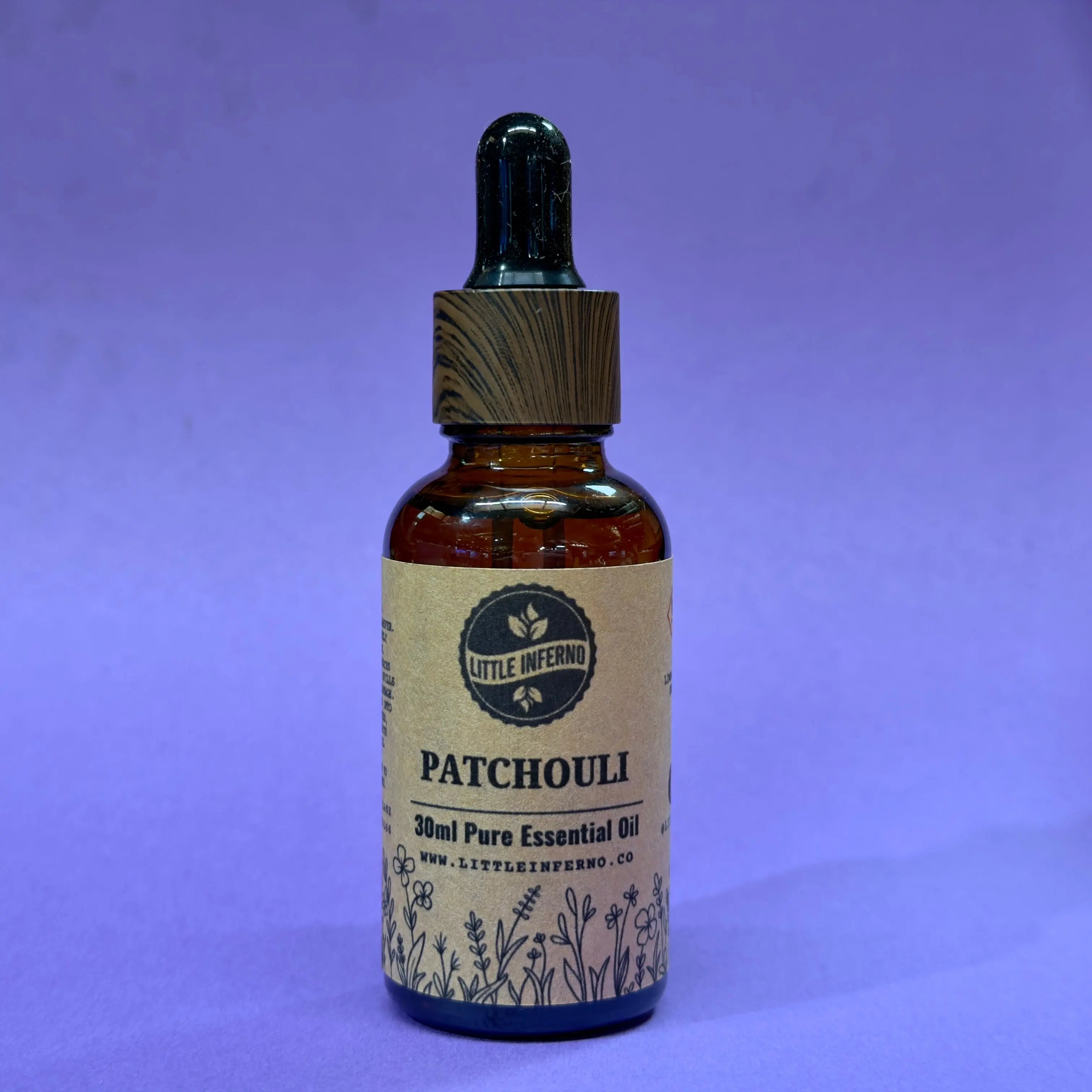 Bottle of patchouli essential oil with a dropper on a purple background