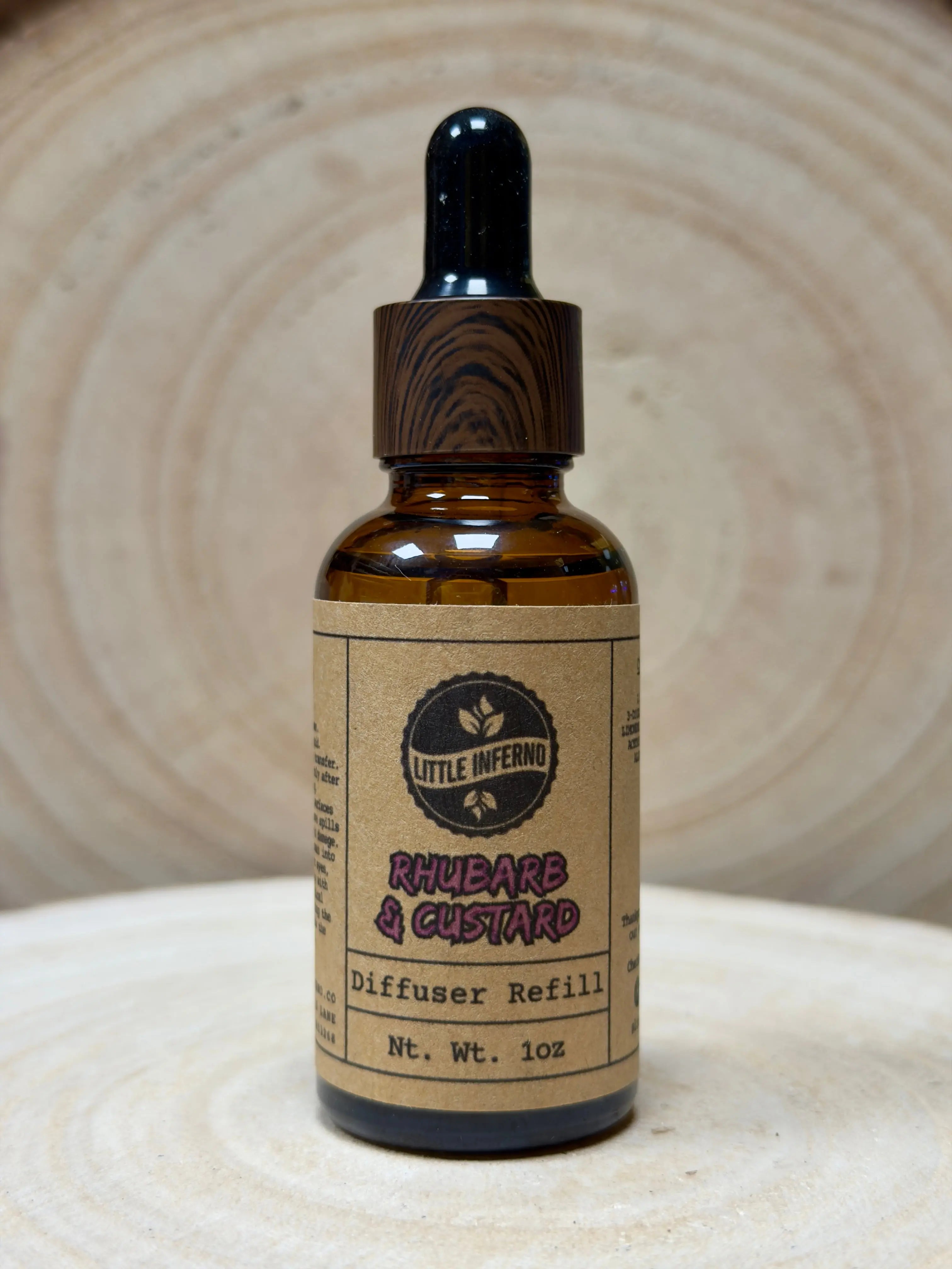 Bottle of rhubarb & custard diffuser refill with a wooden cap on a textured surface
